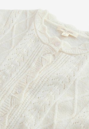 Smetanový pletený cardigan s komplikovanými vzory, s kulatým výstřihem, zapínáním na knoflíky a měkkou texturou. Značka: Laura Ashley.
