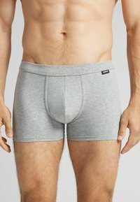 Boxers en coton gris avec une texture douce, une coupe ajustée et une poche profilée. Présente une étiquette de marque noire sur la taille.