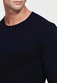 T-shirt a maniche lunghe navy con collo tondo, realizzato in tessuto morbido. Caratterizzato da una texture liscia e un design aderente, che mette in risalto un aspetto semplice e classico.