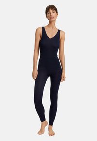 Černý top na ramínka a legíny, vyrobený z měkkého materiálu s hladkou texturou. Má výstřih do V a přiléhavý střih.