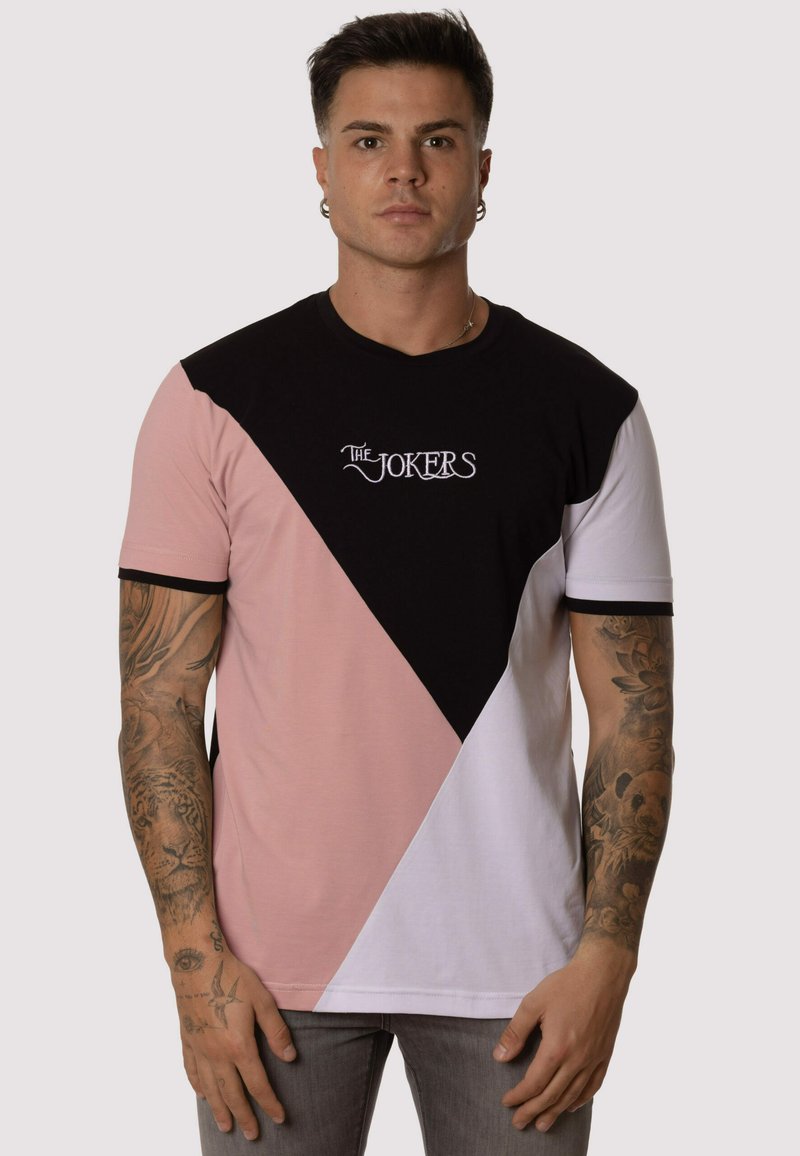 Camiseta de manga corta con un diseño de bloque de color triangular en negro, rosa y blanco, con el texto bordado "LOS JOKERS". Tela de algodón, corte casual.