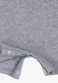 Gr å bomullsstoff med en myk tekstur har en rundet halslinning og to plastknapper nær halsen.