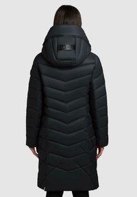 Sort pufferjakke med et chevron- quiltet design, høj krave med logo og en længde til midt på låret for ekstra varme og dækning.