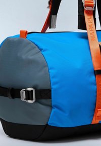 Sac de sport bleu et gris avec un fond noir, doté d'une sangle orange vif et de quincaillerie en argent, fabriqué en matériau nylon durable.