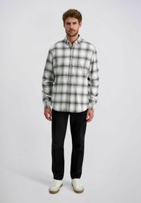 Overhemd met knopen in zwart, wit en grijs ruitpatroon; lange mouwen; rechte zoom; gecombineerd met zwarte broek en witte sneakers.