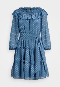 Blå knälång klänning med vita prickar, volangkrage och nederkant, långa ärmar, elastiska manschetter och ett knytbart midjebälte.