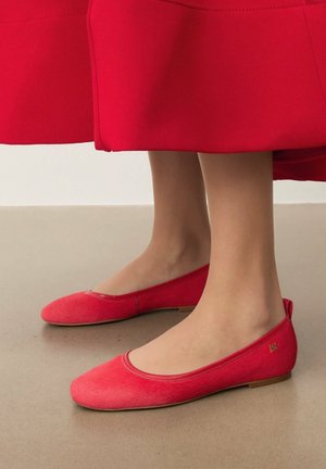Balerini roșii din material textil, cu vârf rotund și toc jos. Partea superioară are o textură fină și există un mic logo auriu pe lateral.