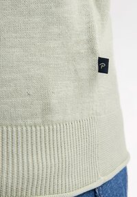 Hellgrüner Strickpullover mit geripptem Saum und Manschetten. Besitzt ein kleines, dunkelblaues Etikett mit dem Buchstaben "P" an der Seite. Weiche Textur.
