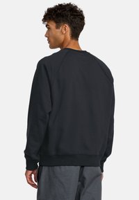 Czarna bluza, okrągły dekolt, rękawy raglanowe, ściągacze przy mankietach i u dołu, wykonana z miękkiego, textured materiału, z czystym, minimalistycznym wzornictwem.
