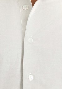 Helle graue Hemden mit Knöpfen, die vertikale Streifen aufweisen, zwei Knöpfe sind vorne sichtbar, und es besteht aus einem weichen, strukturierten Stoff.