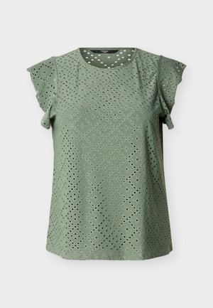 Blouse verte à manches courtes avec encolure ronde et broderie ajourée en motifs losanges et circulaires sur l'ensemble du tissu.