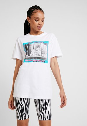 Hvit bomull T-skjorte med grafisk trykk som har et svart-hvitt bilde og fargerik tekst. Sammen med shorts med svart og hvit zebra-stripe.
