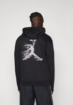 Hoodie noir avec un grand logo Jumpman blanc dans le dos. Fabriqué en tissu doux avec une coupe décontractée et une capuche à cordons.