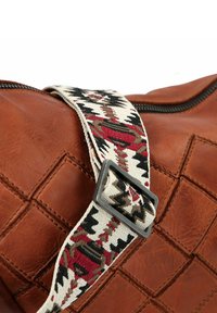 Borsa in pelle marrone con una texture trapuntata. Presenta una tracolla con motivo in crema, rosso e nero con una fibbia in metallo.