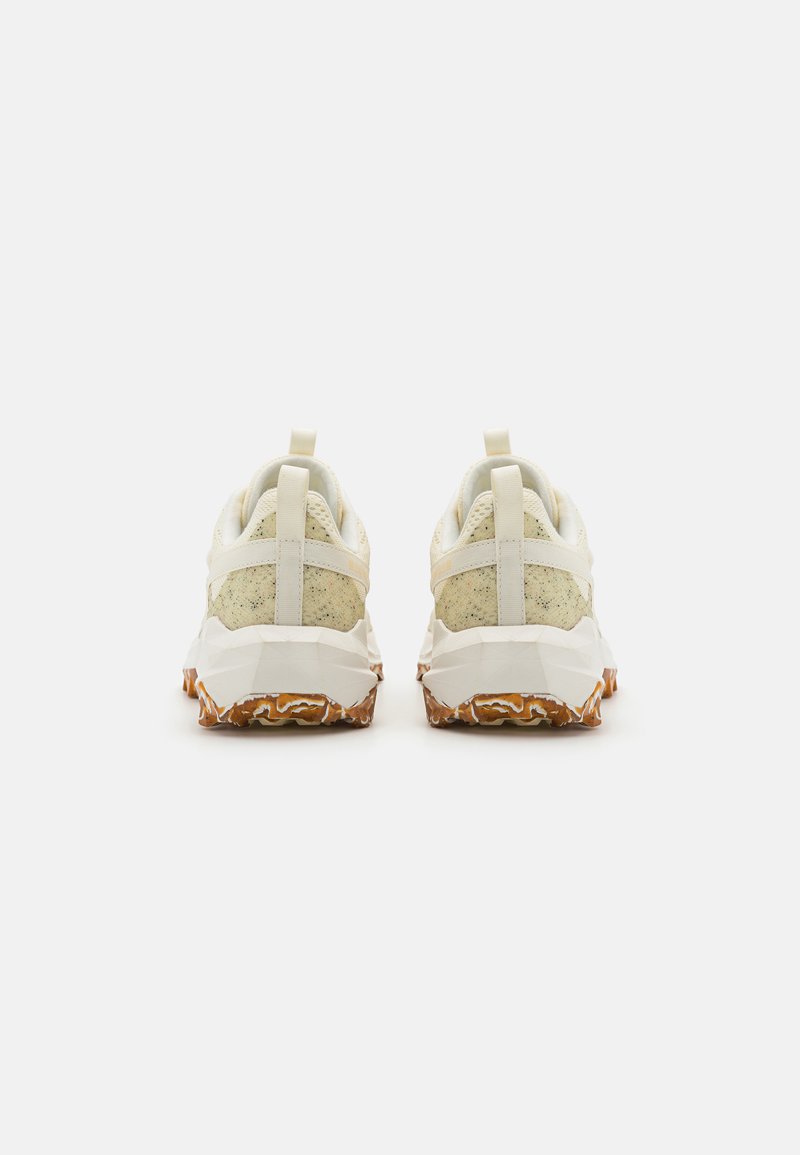 Baskets de sport blanches avec un talon texturé et moucheté, ainsi qu'une semelle multi-facettes. Comprend une languette à l'arrière pour un enfilage facile.