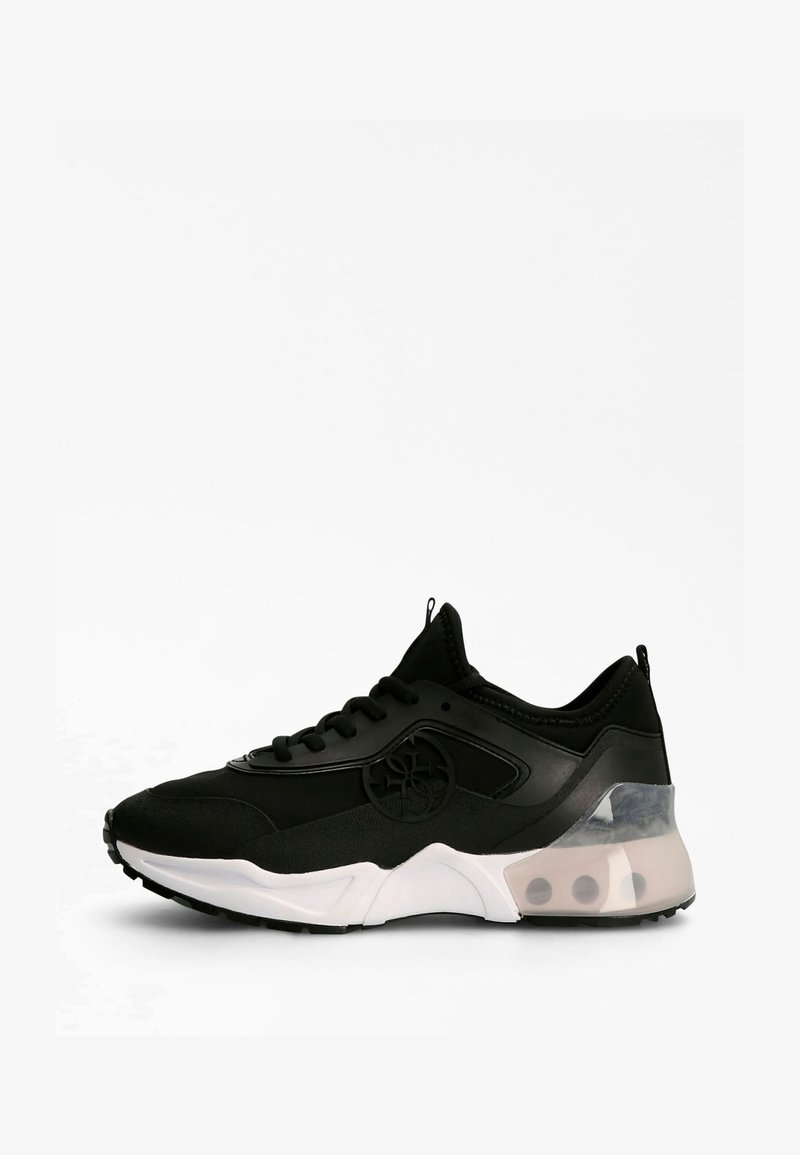 Baskets de sport noires avec semelle blanche, section talon transparente, lacets noirs et détail de logo circulaire sur le côté.