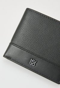 Black wallet with a textured leather finish, featuring a smooth leather accent and embossed "HUGO" logo in silver on the front.