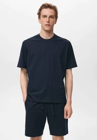 Dunkelblaue Baumwoll-T-Shirt und passende Shorts. Das T-Shirt hat einen Rundhalsausschnitt und kurze Ärmel; die Shorts haben einen elastischen Bund mit Kordelzug.