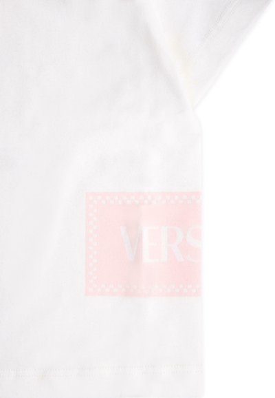 Biała bawełniana koszulka z różowym prostokątnym logo, na którym znajduje się słowo "VERS" w odbijającym świetle w lewym dolnym rogu.