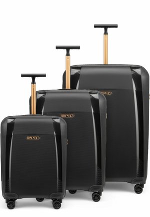 Three black hard-shell suitcases with gold telescopic handles and four spinner wheels, each varying in size, branded "EPIC."