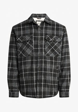 Melna un pelēka svītrota krekls ar divām krūšu kabatām, pogu priekšpusi un mīkstu tekstūru. Rakstā ir kontrastējošas baltas līnijas.