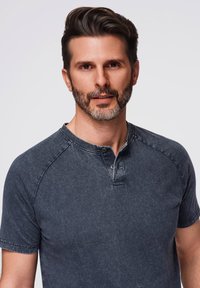 Šedé melírované tričko henley vyrobené z měkké látky, s tříknoflíkovým zapínáním a krátkými rukávy s kontrastním šitím.