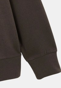 Poignet de sweat-shirt marron foncé avec une texture douce et une finition côtelée, légèrement ample. Design épuré, sans motifs ni accents visibles.