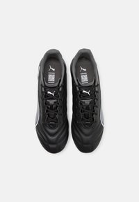 Scarpe sportive nere con tomaia in pelle liscia, dettagli testurizzati, striscia laterale grigia e lacci neri. Presentano un logo sulla linguetta e sulla soletta.