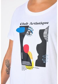 Camiseta blanca de algodón con un diseño gráfico que presenta formas abstractas en azul, rojo, amarillo y negro, y el texto "Club Artistique".