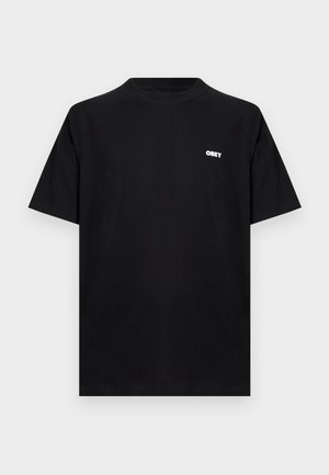 Czarny t-shirt z krótkim rękawem i okrągłym dekoltem, z małym białym logo "OBEY" na lewej piersi, prezentowany na jednolitym jasnoszarym tle.