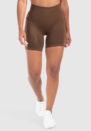 Bruine high-waisted shorts met een gestructureerde afwerking, voorzien van een zijzak en een knielange snit. Gepaard met witte sportschoenen.