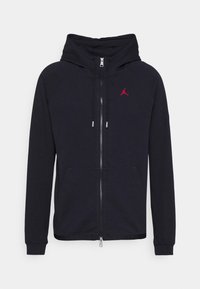 Schwarze Zip-Hoodie mit Kordelzugkapuze, Raglanärmeln, Seitentaschen und einem roten Jordan-Logo auf der Brust. Glatte Stofftextur.