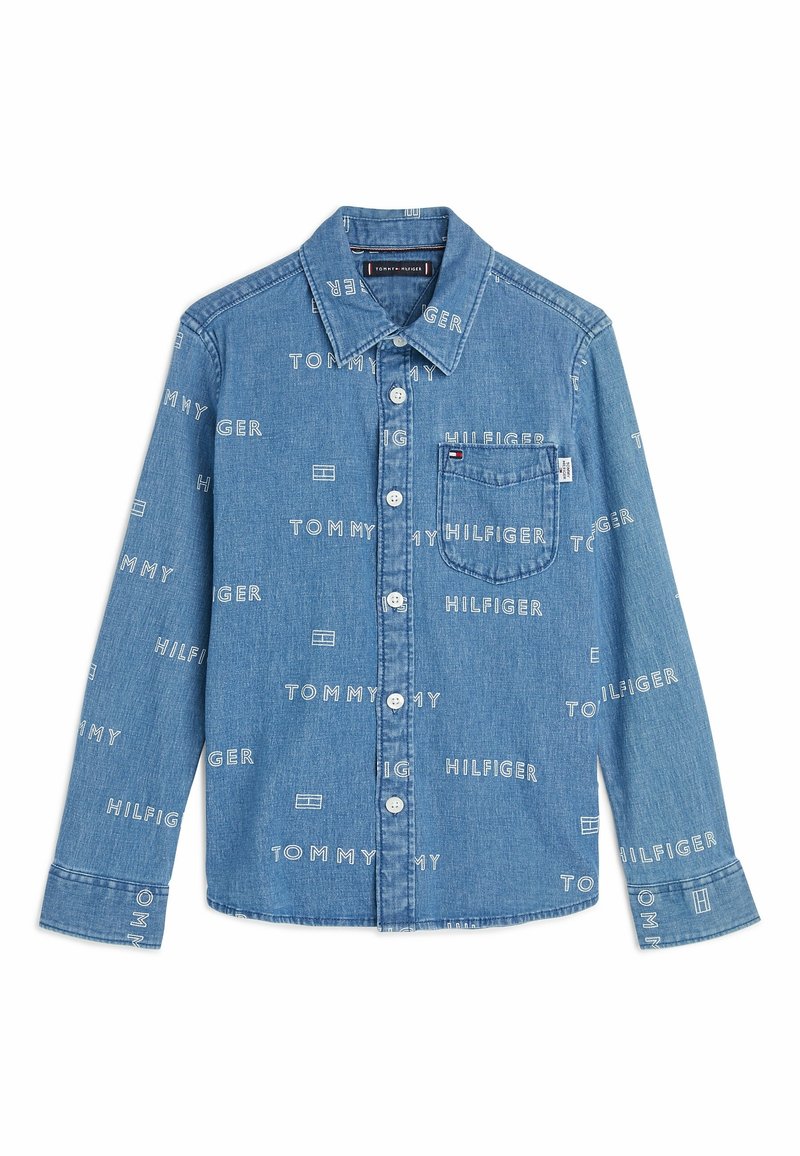 Jeansowa koszula z guzikami w jasnoniebieskim kolorze, z białymi napisami logo "TOMMY" i "HILFIGER." Obejmuje kieszeń na piersi i standardowy kołnierzyk.