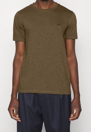 T-shirt olive en jersey à manches courtes avec encolure ronde, coupe slim et un petit logo carré brodé sur la poitrine. Tissu doux et texturé.