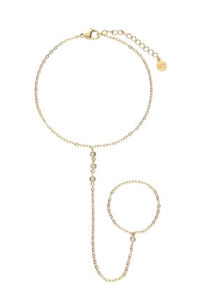 Delicaat gouden ketting handtuig armband met verstelbare sluiting, drie kleine heldere stenen aan de verticale ketting die pols- en vingerringen verbindt.