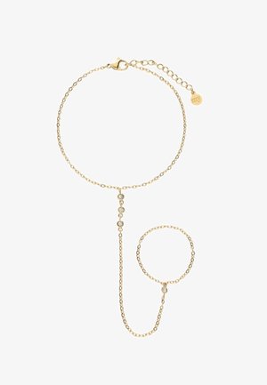 Delicaat gouden ketting handtuig armband met verstelbare sluiting, drie kleine heldere stenen aan de verticale ketting die pols- en vingerringen verbindt.