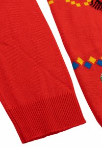 Maniche rosse a maglia con orlo a costine. Presenta motivi e disegni geometrici multicolore, con dettagli in blu, giallo e nero.