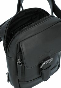 Borsa a tracolla nera in pelle con un compartimento principale con zip, chiusura a pattina e fibbie in metallo. Presenta una superficie testurizzata e cuciture discrete.