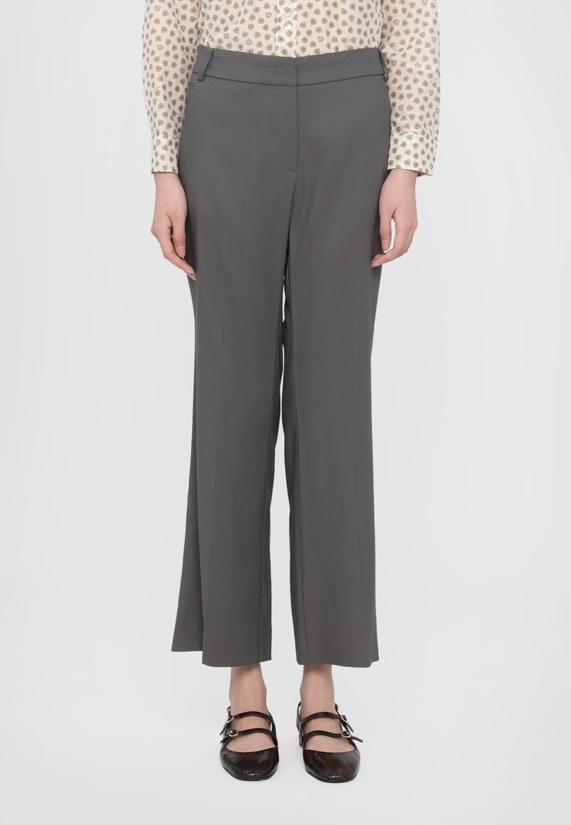 Gray, wide-leg trousers with a smooth texture, featuring a fitted waistband and side pockets. Paired with black, strap shoe.
