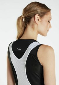 Czarny sportowy top bez rękawów z białą siateczką na plecach, z dekoltem w serek i sportowym wzornictwem. Logo umieszczone przy dekolcie z tyłu.