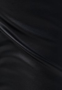 Svart tyg med en slät, något glansig textur, med subtila veck och plisseringar som framhäver dess flexibilitet och mjukhet.