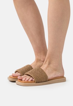 Des sandales à glissière tressées brunes avec une large bride en tissu, une semelle plate beige et un design ouvert à l'avant, idéales pour une utilisation décontractée.