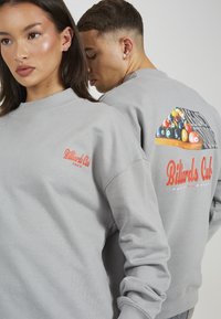 Felpa grigia con collo a costine, grande grafica "Billiards Club" sul retro e un logo più piccolo sul lato anteriore sinistro.