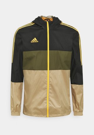 Chaqueta con capucha Adidas negra, verde oliva y beige con cremallera amarilla, rayas amarillas en las mangas y logo de Adidas en el pecho.