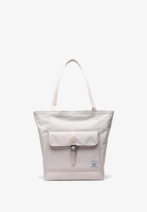 Lys beige tote bag med en struktureret design, stofmateriale, lange håndtag, frontklap sikret med en spænde og et lille brandemblem.
