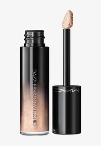 Sombra de ojos líquida en un tubo transparente de gradiente negro con aplicador que muestra maquillaje champán-beige brillante en la punta.