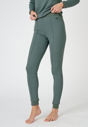 Leggings verdes acanalados con una cinturilla alta, ajuste ceñido y costuras en contraste. Presenta un pequeño logo negro en la cadera izquierda.