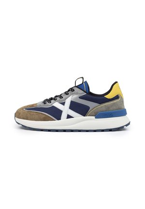 Heren sneaker met een mix van grijs suede en marineblauwe stof, blauwe accenten, een wit logo en een dikke witte zool met een blauwe buitenzool.