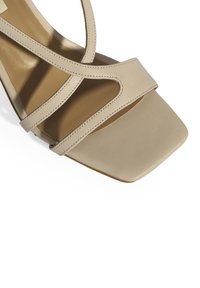 Beige haksandalen met een vierkante neus, een crisscross bandontwerp, een gladde lederen textuur en een effen bruine zool.
