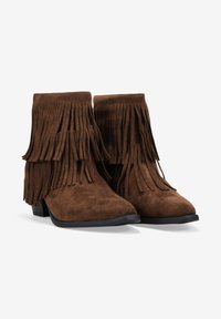 Brown suede boots with fringe detailing, ankle height, pointed toe, and low heel. Textured surface enhances visual interest.